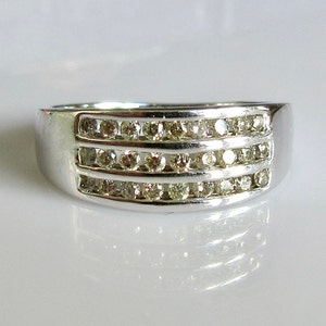 May include: A silver band ring with three rows of small, clear diamonds.