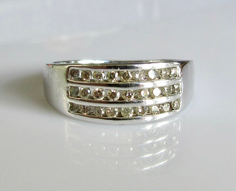 May include: A silver band ring with three rows of small, clear diamonds.