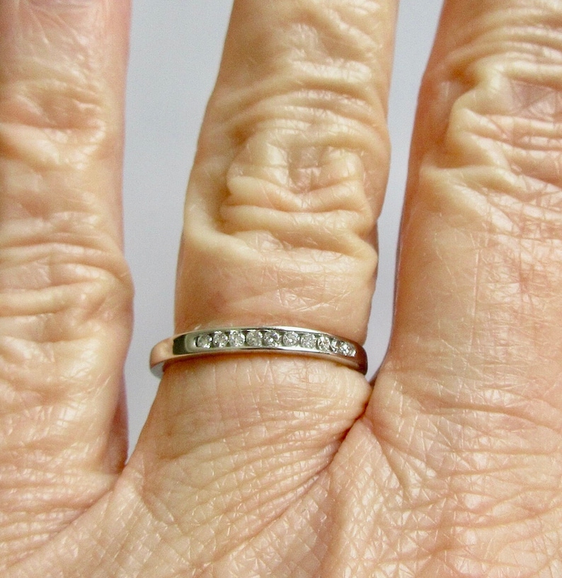 May include: A thin silver band with a row of small diamonds set in the metal.