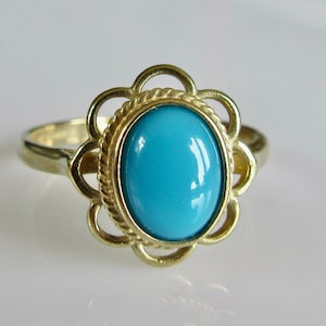 May include: A gold ring with a turquoise stone set in a flower-shaped design.