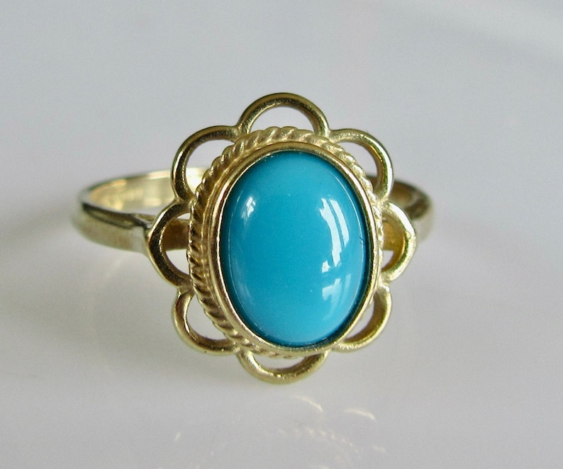 May include: A gold ring with a turquoise stone set in a flower-shaped design.