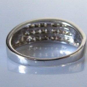 May include: A silver band ring with a row of small diamonds set in the band.