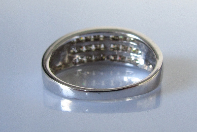 May include: A silver band ring with a row of small diamonds set in the band.