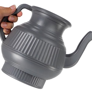 May include: A gray watering can with a handle and a spout. The can has a ribbed design around the middle and a wide base. The handle is arched and the spout curves downward. The can is held by a hand.