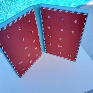 May include: A blue and red advent calendar with 25 numbered doors. The calendar is open to reveal the numbers 1 through 25.
