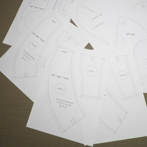 May include: A set of sewing patterns for a garment with instructions for cutting and sewing. The patterns include measurements for different sizes. The patterns are printed on white paper.