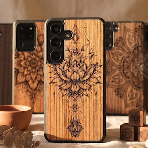 May include: A selection of wooden phone cases with detailed laser-cut patterns. The central case displays a lotus flower design. Other cases feature mandala patterns. Small wooden cubes and stones are arranged nearby, creating a natural, artistic aesthetic.