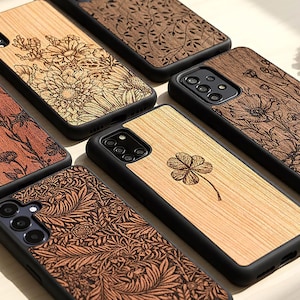 Puede incluir: Una colección de fundas de teléfono de madera con intrincados diseños cortados con láser. Las fundas presentan patrones florales, botánicos y geométricos en tonos marrones y beige. Cada funda tiene un borde negro y está diseñada para varios modelos de teléfono.