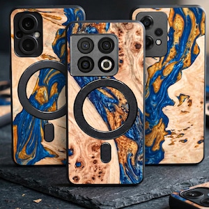 May include: Smartphone cases with a distinctive wood grain pattern. The cases display a blend of light brown, blue, and gold hues, with a black circular feature. The cases have multiple camera lenses and a modern aesthetic.