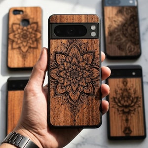 Könnte beinhalten: Eine Sammlung von Handyhüllen aus Holz mit aufwendigen Mandala-Designs. Die Hüllen sind in einem warmen Braunton gehalten, mit einem dunklen, detaillierten Blumenmuster, das in das Holz geätzt ist. Die Hüllen werden in verschiedenen Größen und Stilen gezeigt.