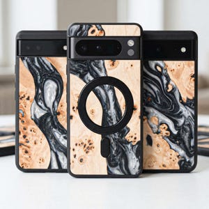 May include: Three phone cases with a wood grain design. The cases have a black border and a black circular magnetic attachment. The wood grain features a mix of light brown, black, and white swirls.