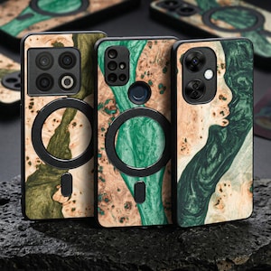 May include: Three mobile phone cases with a distinctive wood grain pattern. The cases display a blend of green, brown, and tan hues. Each case has a black circular feature and a camera aperture. The cases are presented on a dark, textured surface.