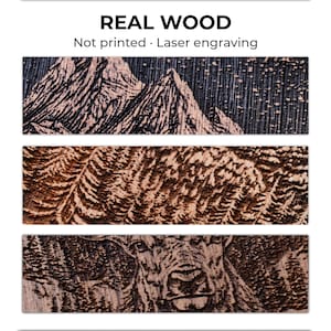 May include: Close-up of three wooden panels with laser-engraved designs. The top panel features a mountain range, the middle panel has a feather-like pattern, and the bottom panel depicts a deer. The text "REAL WOOD" and "Not printed. Laser engraving" are at the top.
