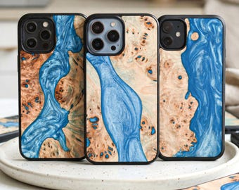 May include: Three phone cases with a unique design. The cases feature a black border with a wood grain pattern in shades of brown and beige, and a flowing blue resin design. The cases are displayed on a white plate.