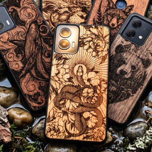 Op de afbeelding: Een verzameling houten telefoonhoesjes met ingewikkelde lasergeëtste ontwerpen. De hoesjes tonen afbeeldingen van een slang, beer, leeuw en wolf, samen met bloemen- en natuurlijke patronen. De hoesjes zijn in verschillende bruin- en zwarttinten.