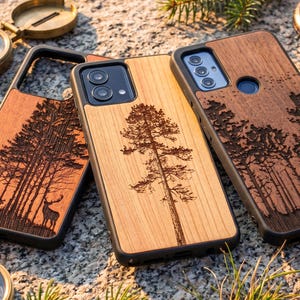 May include: Wooden phone cases with laser-etched forest and tree designs. The cases feature a natural wood grain finish and black edges. One case shows a deer, another a tall tree, and the third a forest scene.