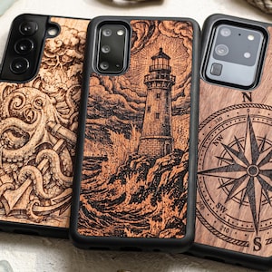 Peut inclure: Trois coques de smartphone avec des cadres noirs et des panneaux arrière en bois. La coque de gauche présente une gravure de pieuvre et d'ancre. Celle du centre montre un phare sur une côte rocheuse avec des vagues. Celle de droite affiche une rose des vents.