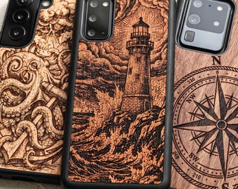 May include: Three smartphone cases with black frames and wood-grain back panels. The left case features an octopus and anchor engraving. The center case displays a lighthouse on a rocky shore with crashing waves. The right case shows a compass rose.