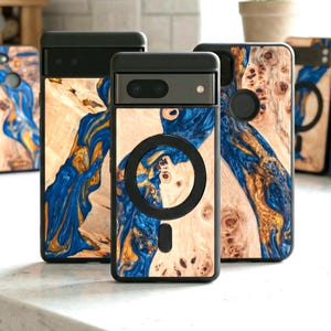 May include: A collection of phone cases with a unique wood grain design. The cases feature a black frame and a natural wood finish with blue and gold resin accents. The cases are designed for a phone with a camera and a circular magnetic attachment.