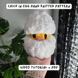 Op de afbeelding: Een handgebreid kuiken in een eipatroon. Het kuiken heeft een gele kop, een oranje snavel en zwarte ogen, omringd door pluizig wit garen. De eierschaal is ook gemaakt van wit garen. Tekst op de afbeelding luidt: "CHICK IN EGG HAND KNITTED PATTERN" en "VIDEO TUTORIAL + PDF".