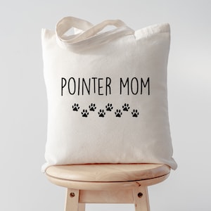 May include: White canvas tote bag with black text that reads "POINTER MOM" and a row of black paw prints below the text.