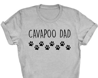 May include: A gray t-shirt with the text "CAVApoo DAD" and a row of paw prints.