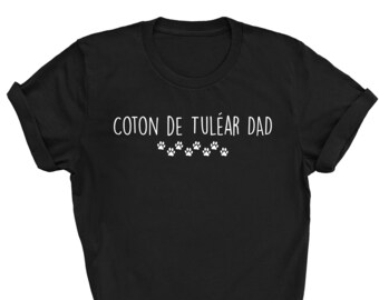 May include: Black t-shirt with white text that reads "Coton de Tulear Dad" and a row of paw prints.