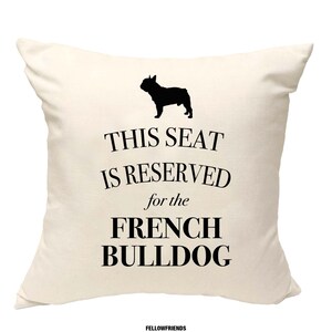 Könnte beinhalten: Ein weißes Kissen mit schwarzem Text, der "Dieser Platz ist für die Französische Bulldogge reserviert" lautet. Oberhalb des Textes befindet sich eine schwarze Silhouette einer Französischen Bulldogge.