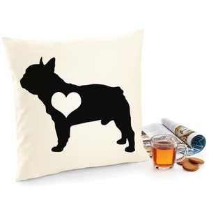 Può includere: Un cuscino bianco con una silhouette nera di un bulldog francese con un cuore bianco sul petto.