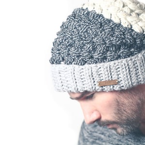 May include: A grey and white crocheted beanie with a brown leather label that says "The Beanie Co."