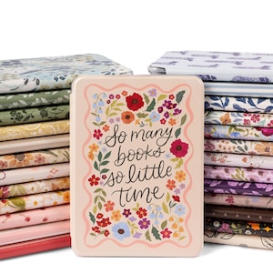 May include: A light pink e-reader case featuring a wavy border and a colorful floral wreath surrounding the black text "So many books so little time." The case is positioned in front of a large stack of various patterned e-reader covers.