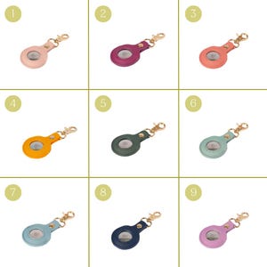 May include: A collection of nine circular faux leather protective cases for tracking devices, each featuring a gold-toned metal lobster clasp, a snap button closure, and a central cutout, presented in various colors including pink, purple, orange, green, and blue.
