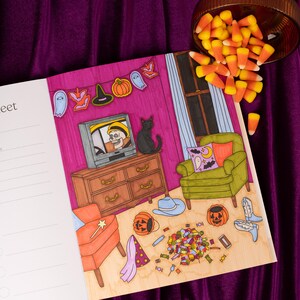 May include: A Halloween-themed illustration featuring a decorated room with a TV showing a skeleton, a black cat, and a green armchair. Candy corn spills from a wooden bowl. The room is decorated with Halloween-themed cutouts and pumpkins.