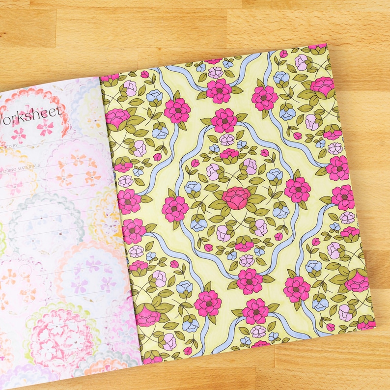May include: Open notebook with a floral design. The right page features a yellow background with pink and blue flowers, green leaves, and blue ribbons. The left page has a worksheet design with pink and white floral patterns. The word "Worksheet" is visible.