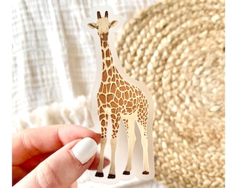 May include: A clear sticker with a detailed illustration of a giraffe. The giraffe is standing with its head held high and its long neck outstretched. The giraffe is brown and white with a spotted pattern.
