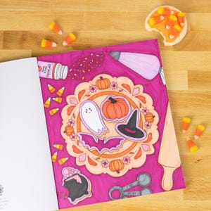 May include: A Halloween-themed illustration with a pink background features a central design of a ghost, pumpkin, witch hat, and bat. Sprinkles, candy corn, and a cookie are scattered around the design. The text "Sprinkles Sweet & Spooky" is visible.