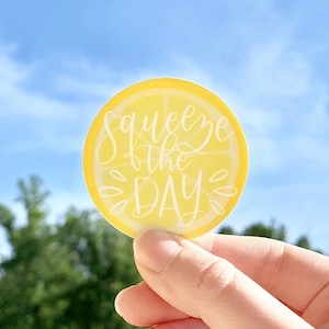 May include: A yellow lemon slice sticker with the text "Squeeze the Day" in white cursive lettering.