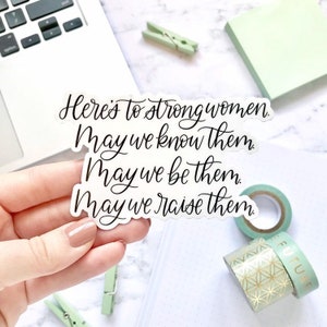 May include: White sticker with black calligraphy that reads "Here's to strong women. May we know them. May we be them. May we raise them."