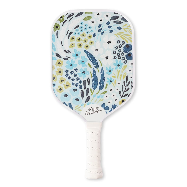 May include: White pickleball paddle with a floral design in shades of blue, yellow, and green. The paddle features the text "elyse breadanne" and a white grip.