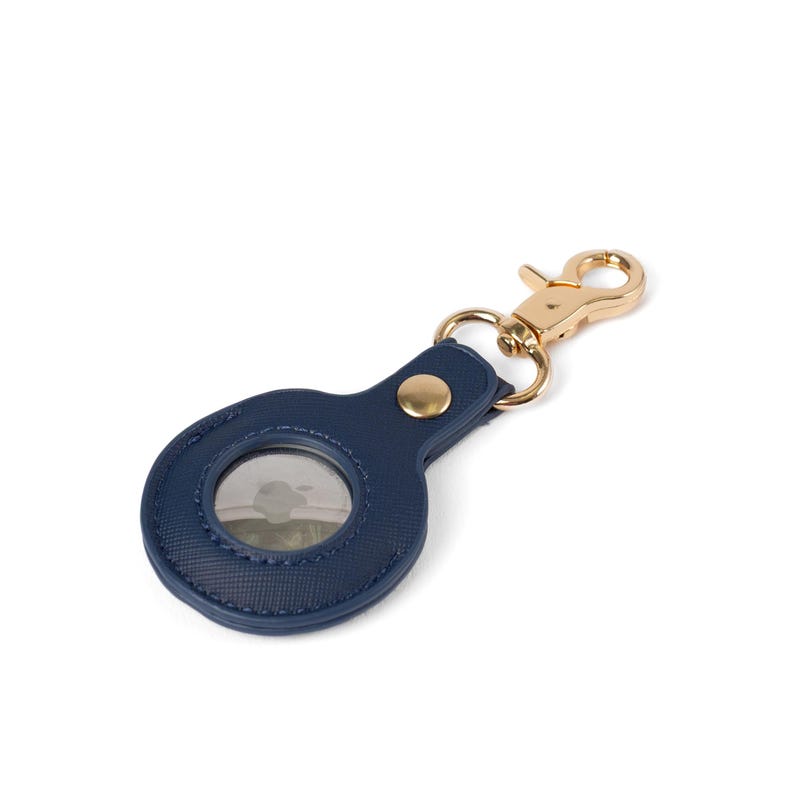 May include: A navy blue circular protective case for a tracking device, featuring a textured surface, a gold-toned metal snap button, and a matching gold-toned lobster claw clasp attached to a small metal ring for secure fastening to items.