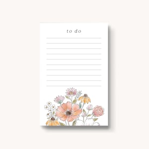 May include: A white notepad with the words "to do" printed at the top. The notepad has lined paper and a floral design at the bottom. The flowers are pink, orange, and yellow.