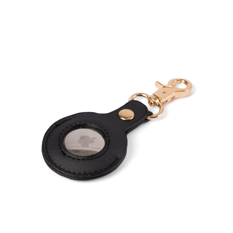 May include: A black textured protective case for a circular tracking device, featuring a gold-toned metal snap button closure and a matching gold-toned lobster claw clasp attached to a small metal ring for secure fastening to keys or bags.