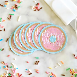 May include: A set of six donut-themed stickers with a blue background and the text "donut worry" in white script. The donuts are pink with pink and white sprinkles.