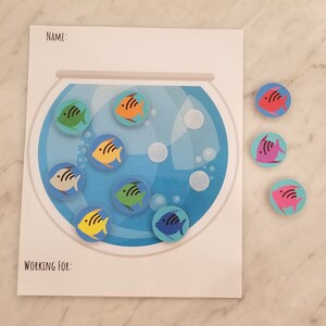 Może przedstawiać: Drukowana karta pracy z napisami "NAME:" i "WORKING FOR:" u góry. Karta pracy przedstawia niebieską akwarium z kolorowymi naklejkami ryb. Są też kolorowe naklejki ryb poza akwarium.