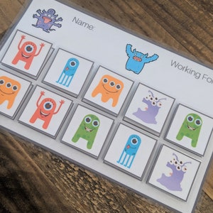 May include: A set of colorful monster-themed matching game tiles. The tiles feature different monsters with various colors, eyes, and expressions. The game includes a title card with the words "Name" and "Working For".