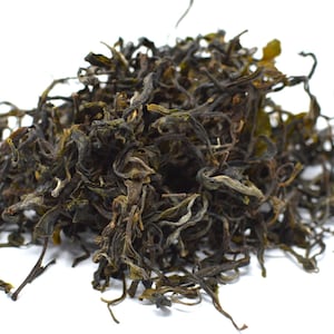 May include: Loose leaf black tea with long, twisted leaves. The tea is a dark green and brown color.