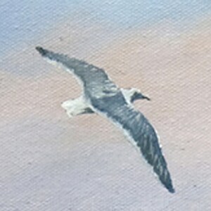May include: An oil painting of a seagull in flight. The bird has gray and white feathers, with its wings spread wide against a backdrop of a light blue and peach sky. The artwork captures the seagull's graceful movement.