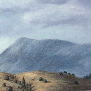 May include: A misty mountain range with a blue-grey hue, partially obscured by clouds. The foreground features a grassy hillside with a few small trees.