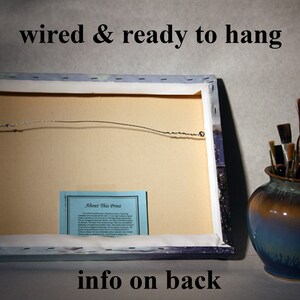 May include: The back of a canvas print with a wire hanger attached. The print has a blue and white background with a small blue card that says "About This Print" on it. The text "wired & ready to hang" is printed at the top of the image. The text "info on back" is printed at the bottom of the image.