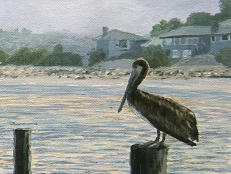 May include: An oil painting depicts a brown pelican perched on a wooden piling in the water. The background shows a shoreline with houses and trees under a hazy sky. The water has subtle reflections.
